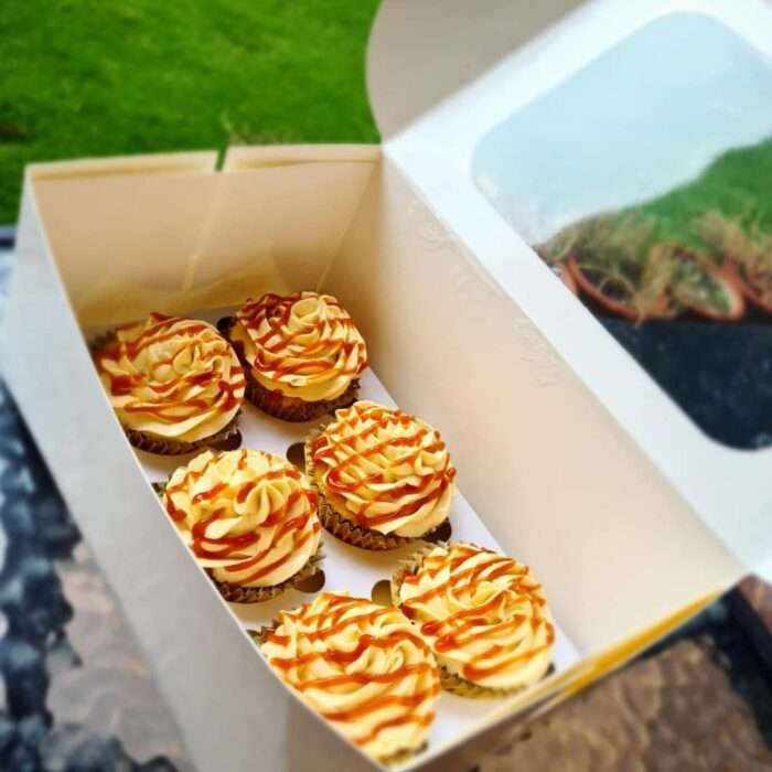 Box of homemade caramel cupcakes with cream frosting and caramel drizzle in Lahore