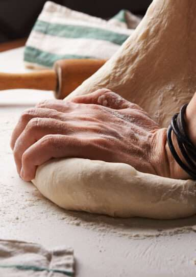 Hands kneading fresh bread dough in homemade bakery kitchen Lahore